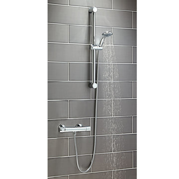 Shower system with handheld shower head and control handle on a tiled wall.