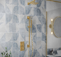 Bathroom with geometric tile pattern, gold shower fixtures, and a round mirror.