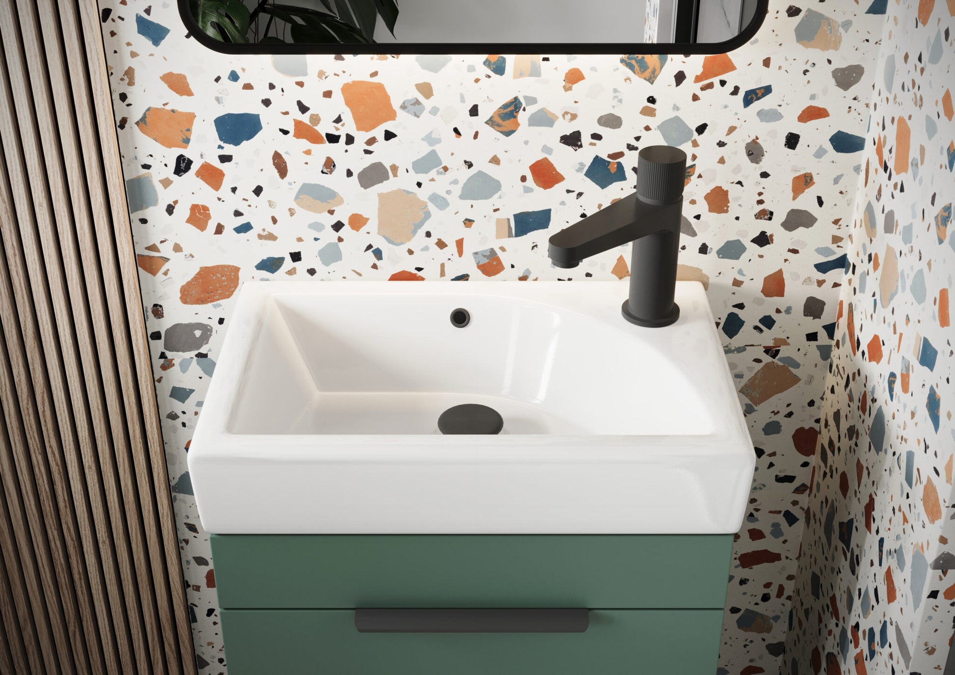 Bathroom vanity with white sink and green base against a terrazzo-patterned wall.