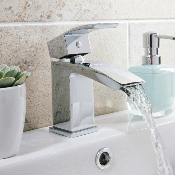 Chrome bathroom faucet set with drain assembly on a white background